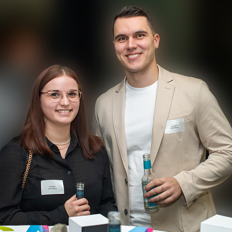 Eine Studentin und ein Student stehen nebeneinander in festlicher Atmosphäre